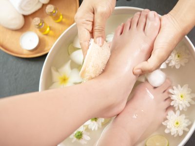 foot washing in spa before treatment. spa treatment and product for female feet and hand spa. white flowers in ceramic bowl with water for aroma therapy at spa.